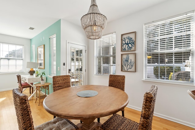 dining room with light wood-type flooring, visible vents, baseboards, and an inviting chandelier