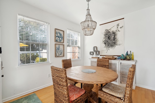 dining space with baseboards, a chandelier, and light wood finished floors