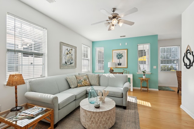 living area with a ceiling fan, visible vents, baseboards, and light wood-type flooring