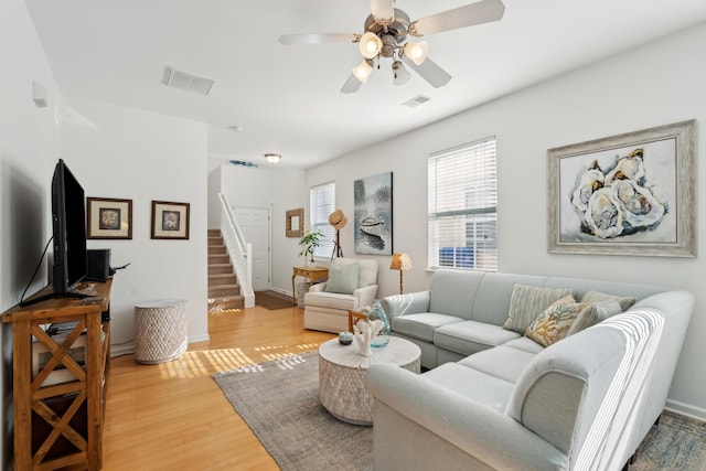 living area with visible vents, stairway, ceiling fan, and wood finished floors