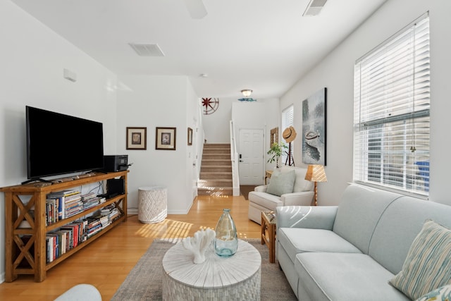 living room with stairway, wood finished floors, and visible vents