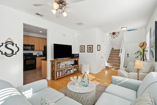 living area featuring visible vents, a ceiling fan, stairs, and light wood-style floors