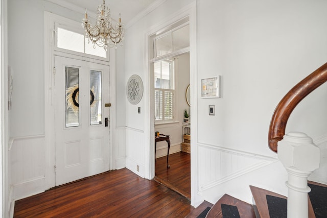 foyer entrance with dark hardwood / wood-style floors, crown molding, and a chandelier