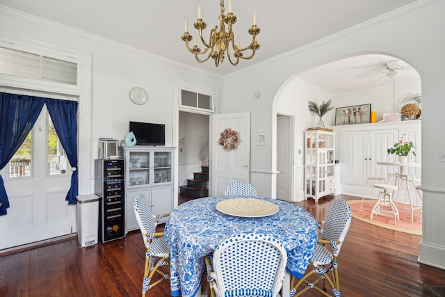 dining space featuring ceiling fan with notable chandelier, ornamental molding, and dark wood-type flooring