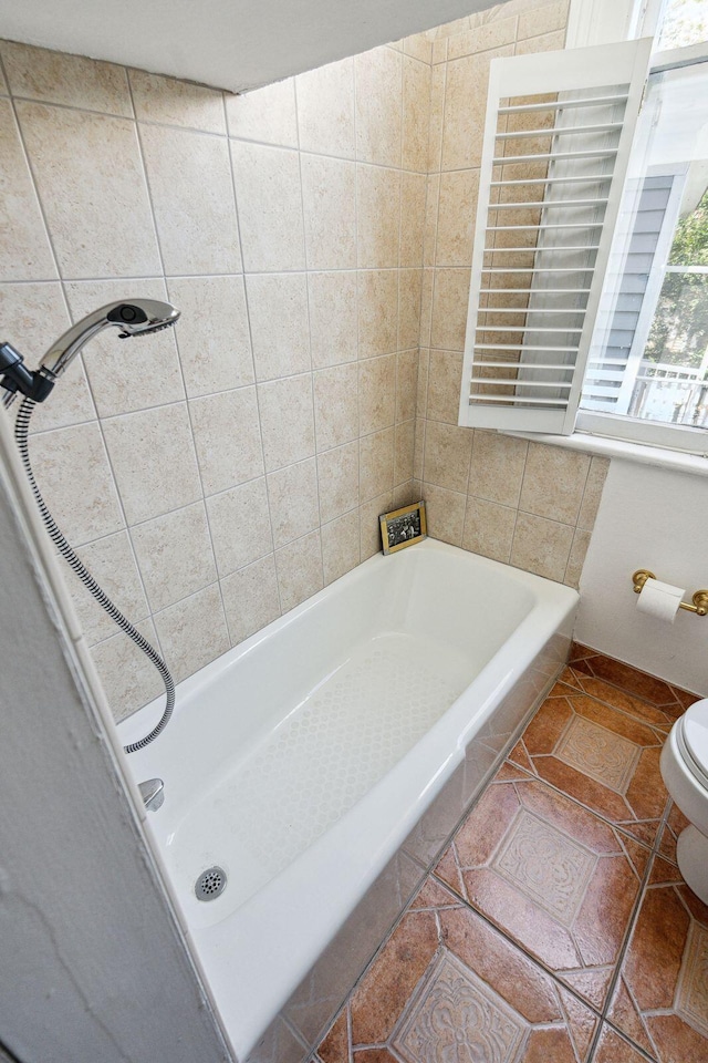 bathroom with tile patterned floors, toilet, and tiled shower / bath