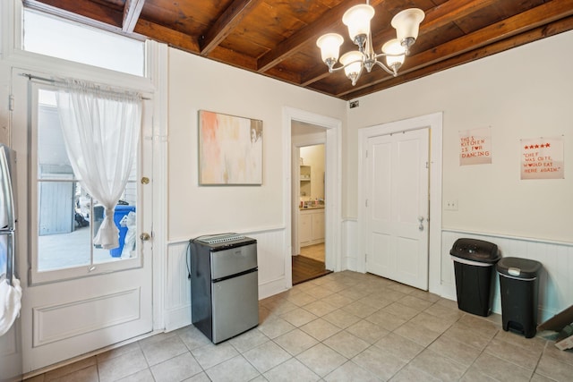 foyer featuring beamed ceiling, a healthy amount of sunlight, a notable chandelier, and wood ceiling