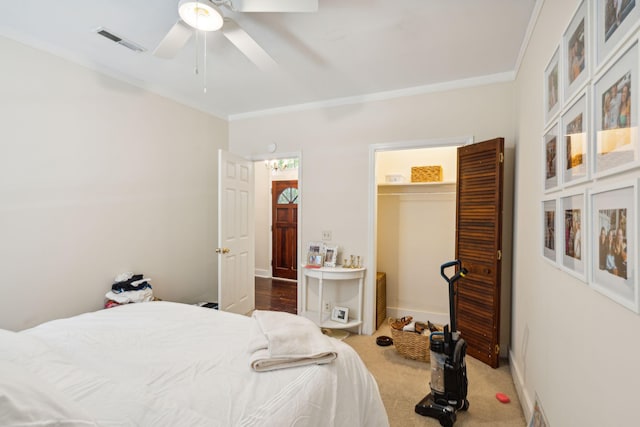 carpeted bedroom featuring ceiling fan, a spacious closet, crown molding, and a closet