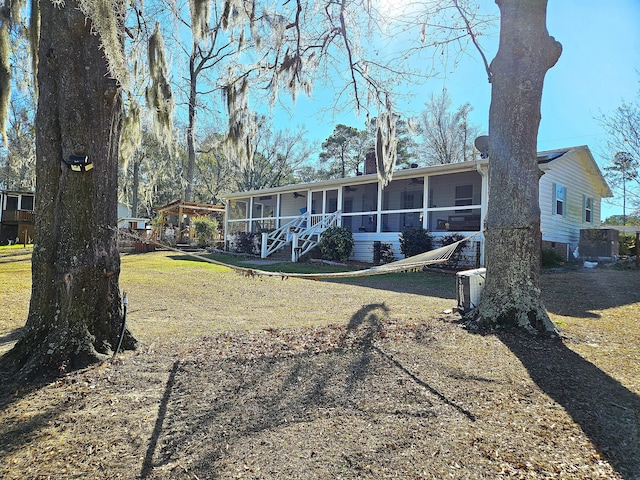 rear view of property featuring a yard and a sunroom