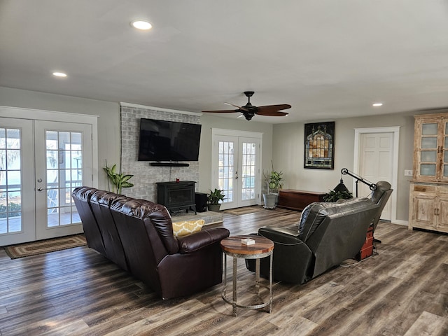 living area featuring baseboards, dark wood finished floors, a wood stove, french doors, and recessed lighting