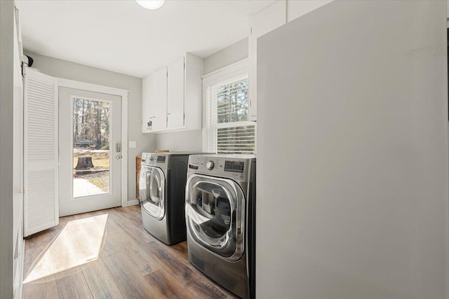 laundry room with cabinet space, wood finished floors, and washing machine and clothes dryer