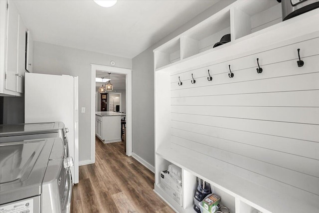 mudroom featuring dark wood finished floors, baseboards, and separate washer and dryer