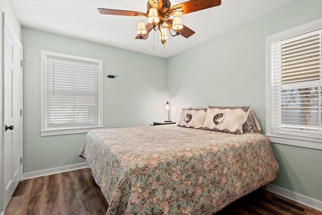 bedroom with dark wood-style flooring, visible vents, baseboards, and multiple windows