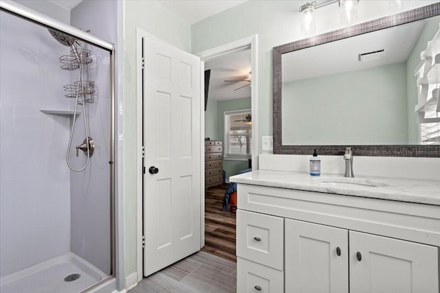 bathroom featuring a stall shower, wood finished floors, connected bathroom, and vanity