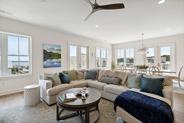 living room featuring ceiling fan with notable chandelier, a wealth of natural light, and wood-type flooring