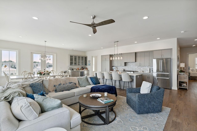 living room featuring ceiling fan with notable chandelier and dark hardwood / wood-style flooring