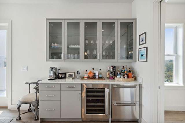 bar featuring gray cabinetry, wine cooler, and wood-type flooring