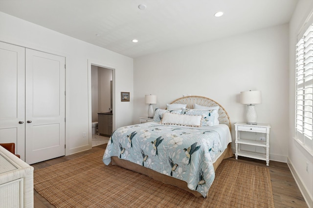 bedroom with multiple windows, connected bathroom, hardwood / wood-style floors, and a closet