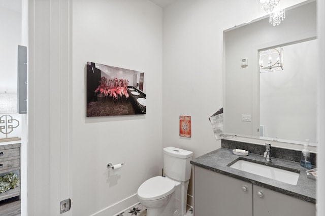 bathroom with toilet, a notable chandelier, and vanity