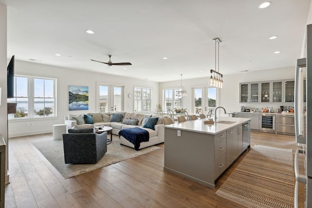 kitchen with a kitchen island with sink, ceiling fan with notable chandelier, light hardwood / wood-style flooring, and wine cooler