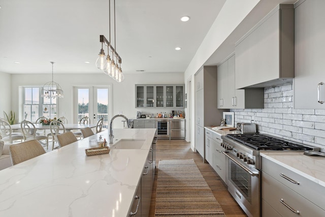 kitchen with a notable chandelier, stainless steel range, sink, light stone countertops, and dark hardwood / wood-style floors