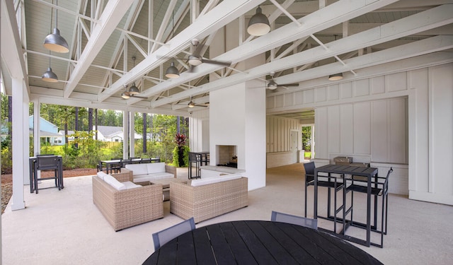 view of patio / terrace with an outdoor living space with a fireplace, a ceiling fan, and outdoor dining space