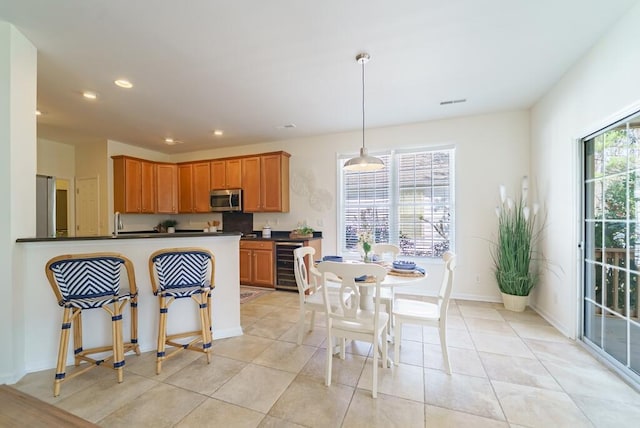 kitchen featuring decorative light fixtures, dark countertops, recessed lighting, appliances with stainless steel finishes, and beverage cooler