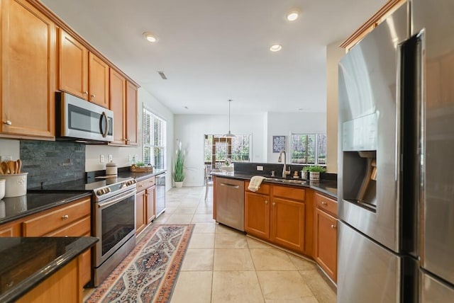 kitchen with appliances with stainless steel finishes, brown cabinetry, a sink, and tasteful backsplash