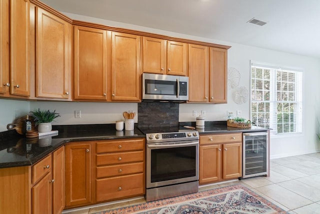 kitchen featuring brown cabinets, visible vents, appliances with stainless steel finishes, light tile patterned flooring, and beverage cooler