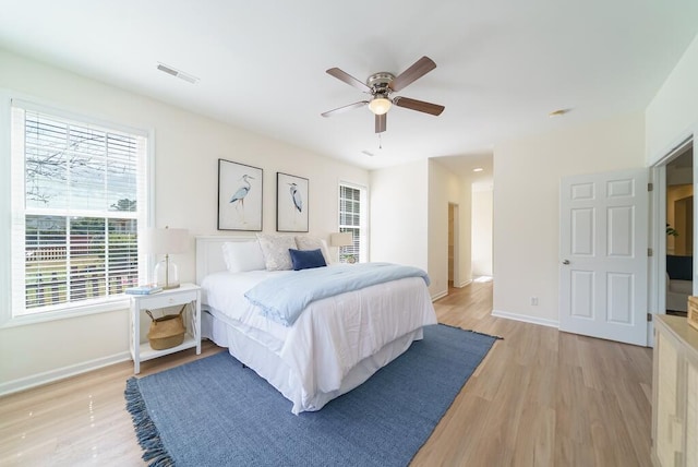 bedroom featuring visible vents, a ceiling fan, light wood-style flooring, and baseboards