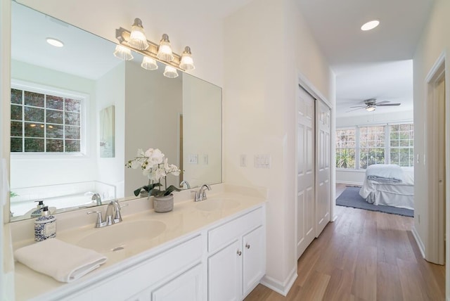 bathroom featuring double vanity, recessed lighting, a sink, and wood finished floors