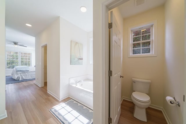 ensuite bathroom featuring visible vents, a garden tub, toilet, and wood finished floors