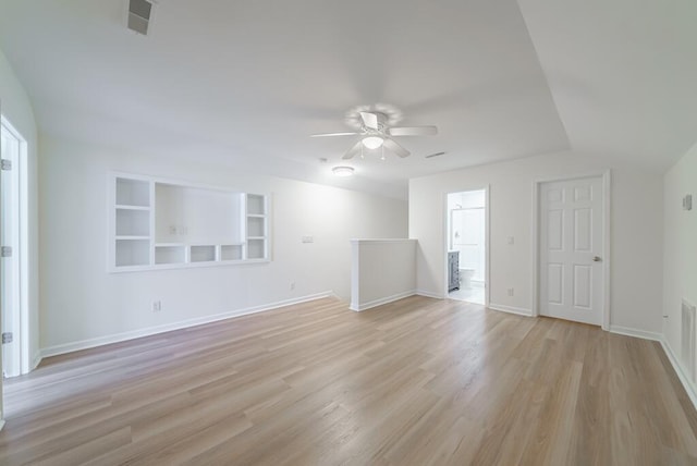 empty room featuring built in shelves, light wood finished floors, visible vents, and baseboards