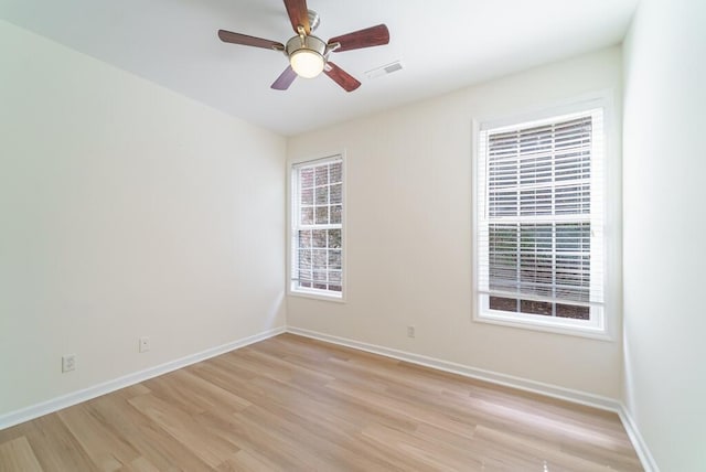 empty room featuring light wood-style floors, visible vents, baseboards, and a ceiling fan