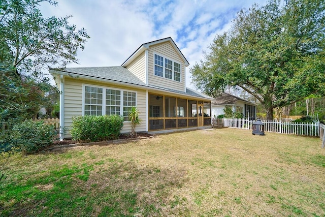 rear view of house with a sunroom, roof with shingles, a lawn, and fence