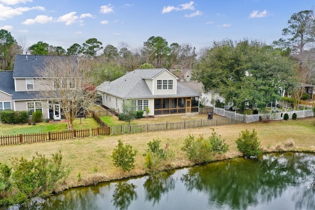 rear view of property with a fenced backyard, a yard, and a water view