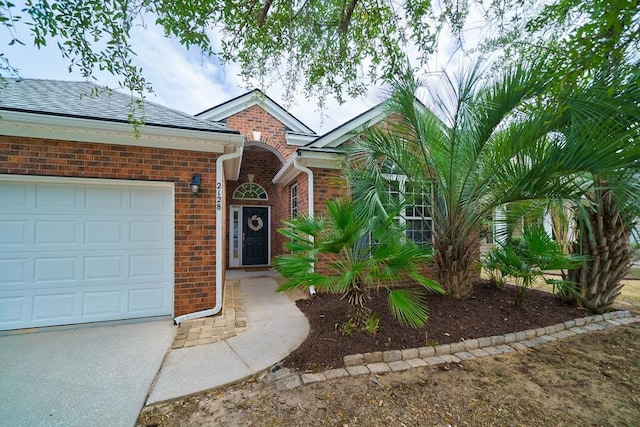 view of front of home with a garage, concrete driveway, brick siding, and a shingled roof