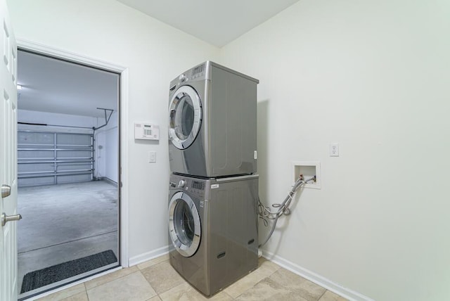 laundry area with a garage, laundry area, stacked washer and clothes dryer, and baseboards