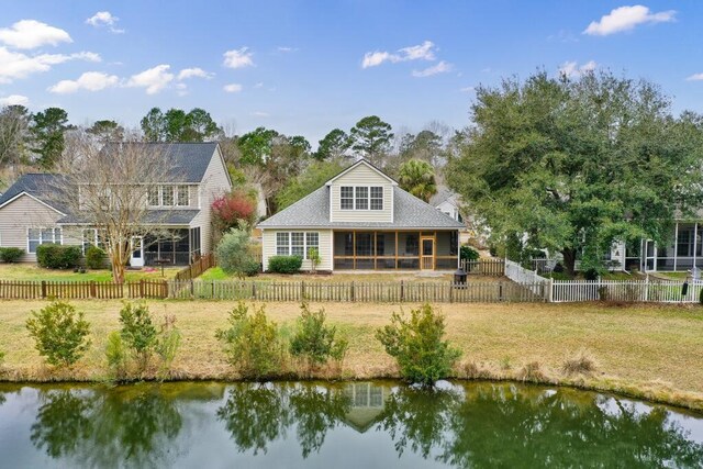 back of house with a sunroom, a water view, a yard, and a fenced backyard