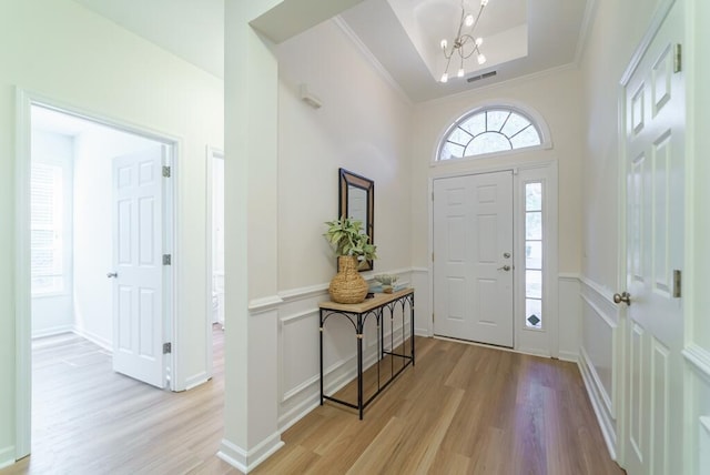 entrance foyer with light wood-style floors, a tray ceiling, visible vents, and baseboards