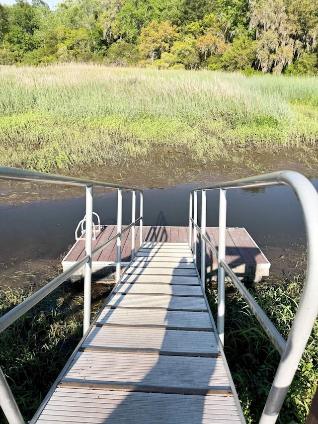 view of dock with a forest view and a water view