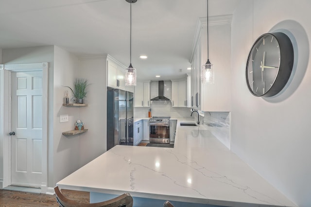 kitchen with built in fridge, sink, wall chimney exhaust hood, decorative light fixtures, and stainless steel range oven