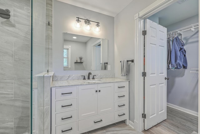 bathroom featuring tiled shower, vanity, and hardwood / wood-style flooring