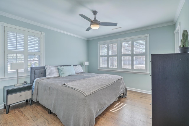 bedroom with multiple windows, light hardwood / wood-style floors, ceiling fan, and ornamental molding