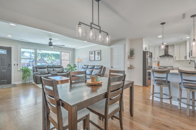 dining room featuring ceiling fan, light hardwood / wood-style flooring, crown molding, and sink