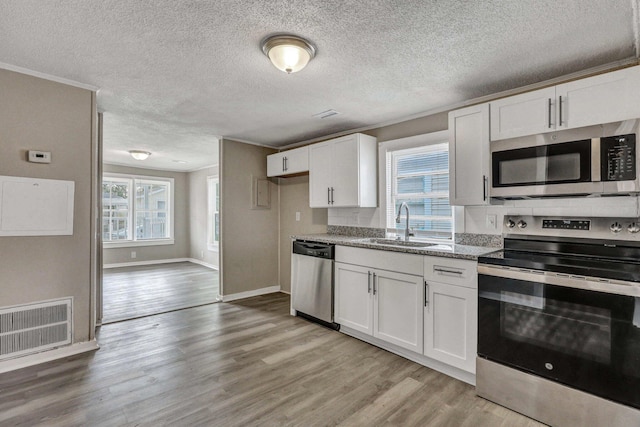 kitchen featuring sink, light hardwood / wood-style flooring, appliances with stainless steel finishes, light stone counters, and white cabinets