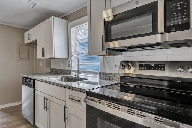 kitchen with sink, hardwood / wood-style flooring, stainless steel appliances, white cabinets, and stone countertops