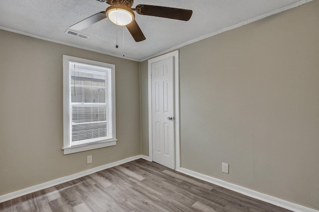 empty room featuring ornamental molding, a textured ceiling, and light hardwood / wood-style floors