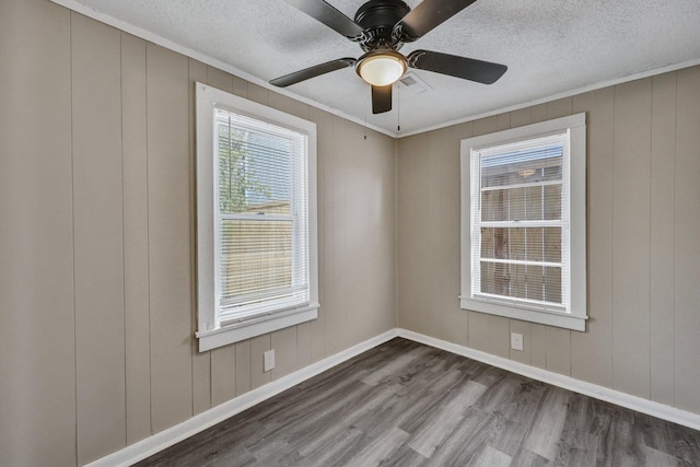 unfurnished room featuring ceiling fan, dark wood-type flooring, ornamental molding, and a textured ceiling