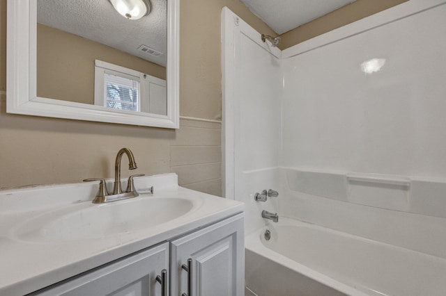 bathroom with shower / bath combination, vanity, and a textured ceiling