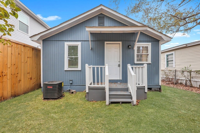 rear view of property featuring an outbuilding, a lawn, and central air condition unit